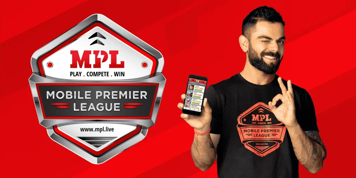 Man in an MPL shirt holding a phone in front of Mobile Premier League branding Man in an MPL shirt holding a phone in front of Mobile Premier League branding